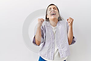 Beautiful middle age hispanic woman standing over isolated background pointing to the back behind with hand and thumbs up, smiling