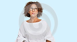 Beautiful middle age mature woman wearing casual clothes and glasses smiling looking to the side and staring away thinking