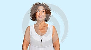 Beautiful middle age mature woman wearing casual white shirt smiling looking to the side and staring away thinking