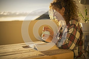 Beautiful middle age woman read a book and relax enjoy the leisure acitivity at home on the terrace- sunset light in the