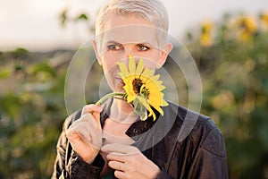 Beautiful middle age woman in a rural field scene outdoors standing between sunflowers