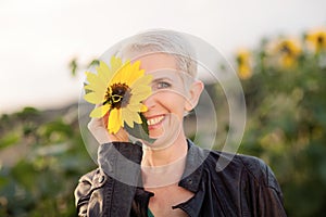 Beautiful middle age woman in a rural field scene outdoors standing between sunflowers