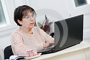 Beautiful middle age woman using laptop in home