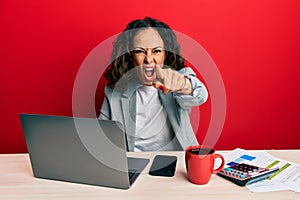 Beautiful middle age woman working at the office drinking a cup of coffee pointing displeased and frustrated to the camera, angry