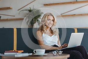 beautiful middle aged businesswoman using laptop and smiling at camera