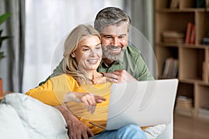 Beautiful Middle Aged Couple With Laptop Computer Resting Together At Home