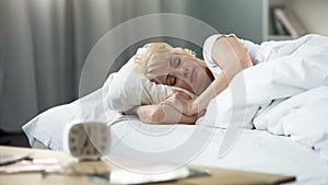 Beautiful middle-aged lady sleeping in bed, sleep cycle, peaceful rest, health