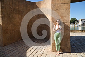 beautiful middle-aged woman doing yoga in the street. The woman does meditation and relaxation exercises with closed eyes and