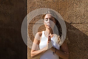 beautiful middle-aged woman doing yoga in the street. The woman does meditation and relaxation exercises with closed eyes and