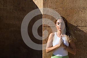 beautiful middle-aged woman doing yoga in the street. The woman does meditation and relaxation exercises with closed eyes and