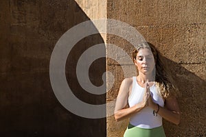 beautiful middle-aged woman doing yoga in the street. The woman does meditation and relaxation exercises with closed eyes and