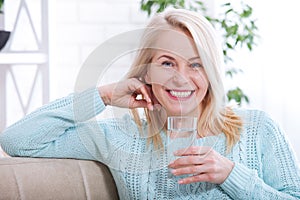 Beautiful middle aged woman drinking water in the morning