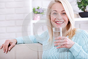 Beautiful middle aged woman drinking water in the morning