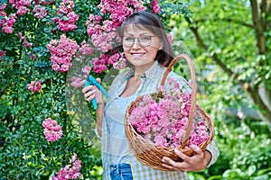 Beautiful middle aged woman in garden caring for flowering plants