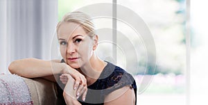 Beautiful middle-aged woman looking in camera in living room