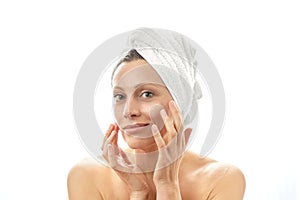 A beautiful middle-aged woman looks after her face. It is consumed with cream and makes facial skin massage. Isolated white