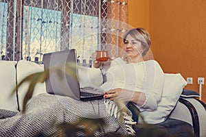 Beautiful middle aged woman using laptop and drinking tea