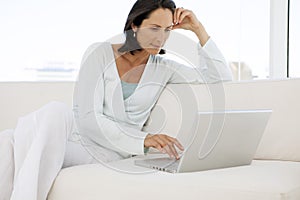 Beautiful middle aged woman using laptop at home