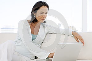 Beautiful middle aged woman using laptop at home