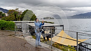 beautiful middle aged woman using mobile phone to take photographs outdoors in the rain