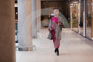 Beautiful middle aged Woman Wearing Fashionable Clothes long burgundy silk dress, leopard print coat jacket, black boots