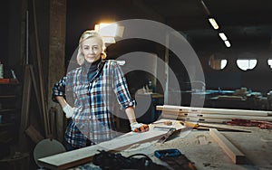 Beautiful middle aged woman worker posing against background of a woodworking workshop. Concept of motivated women, gender