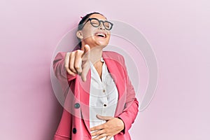 Beautiful middle eastern woman wearing business jacket and glasses laughing at you, pointing finger to the camera with hand over