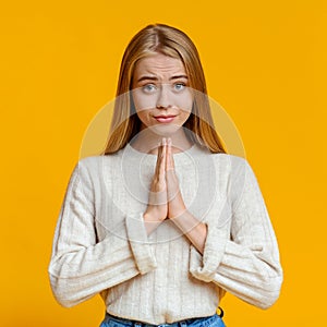 Beautiful millennial girl praying with hands clasped near face