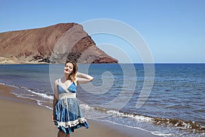 Beautiful millennial woman holding her hair with one hand and the head tilted with her eyes closed at Playa la Tejita, Tenerife photo