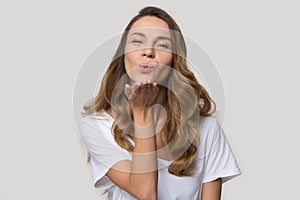 Beautiful millennial woman makes air kiss pose in studio