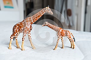 Beautiful miniature giraffes mother and baby standing up made of rubber or plastic