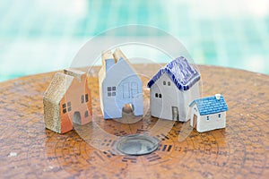 Beautiful miniature house on ancient wooden feng shui compass over blurred blue water background