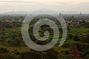 Beautiful misty view of Bagan temples and pagodas in green valley just before sunrise, Burma Myanmar. Fog over valley