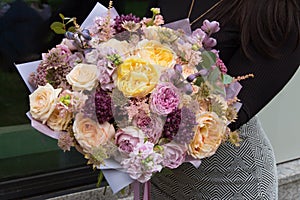 Beautiful mixed flowers bouquet with yellow and pink roses in the hands, gift