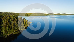 A beautiful mixed forest along the shore of the huge calm lake. Blue sky. Nature background