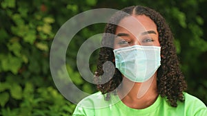 Beautiful mixed race African American girl biracial teenager young woman outside wearing a face mask during COVID-19 Coronavirus p