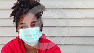 Beautiful mixed race African American girl biracial teenager young woman outside wearing a face mask outside
