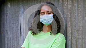 Beautiful mixed race African American girl biracial teenager young woman outside wearing a face mask in an urban city setting
