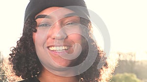 Beautiful mixed race African American girl teenager young woman laughing backlit by the sun in evening sunshine