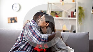 Beautiful mixed-race couple hugging with bouquet of tulips, loving relationship