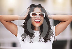 Beautiful mixed race fashion woman wearing sunglasses while standing outside. Young hispanic woman looking stylish and