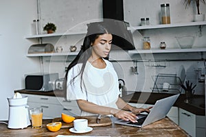 Beautiful mixed race girl in white robe using laptop in morning