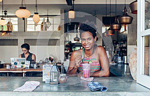 Beautiful mixed race pacific islander girl in vegetarian cafe for breakfast with fresh mix smoothie in glass