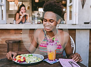 Beautiful mixed race pacific islander girl in vegetarian cafe for breakfast with wrap and salad and fresh mix smoothie in glass