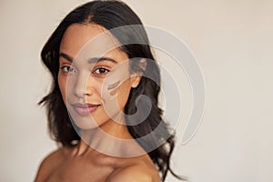 Beautiful mixed race woman trying foundation shades on cheek