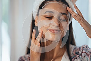 Beautiful model applying cosmetic cream treatment on her face