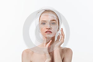 Beautiful model applying cosmetic cream treatment on her face on white.