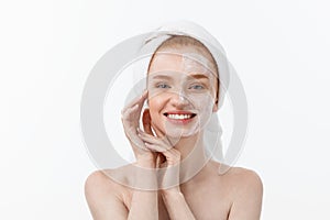 Beautiful model applying cosmetic cream treatment on her face on white.