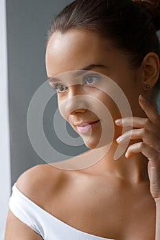 Beautiful model applying cosmetic cream treatment on her face on white background.Skin care. Moisturizer cream