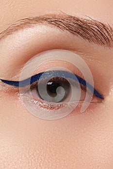 Beautiful model applying eyeliner close-up on eye. Make-up photo